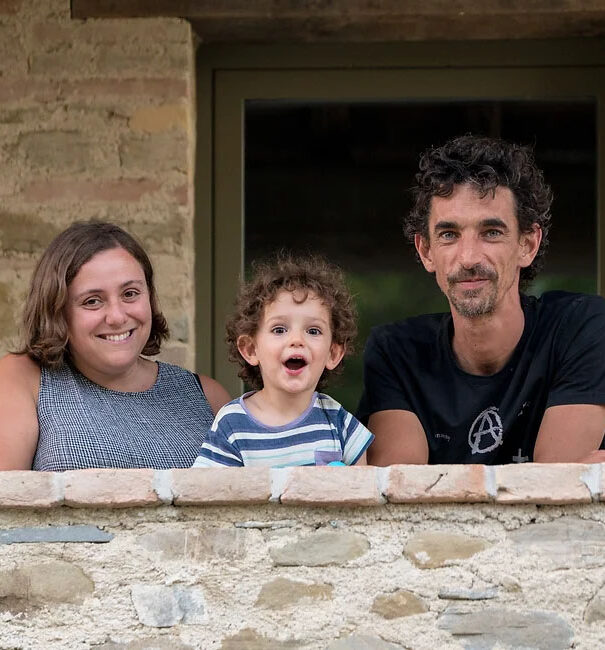 Foto che ritrae Claudia (a sinistra), Stefano (a destra) e il piccolo Lorenzo (al centro) mentre si affacciano da una terrazza. Loro sono i proprietari e gestori dell’Agriturismo Montelovesco.