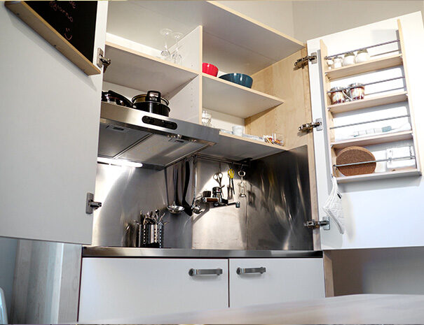 Foto dell’interno di un mobile della cucina della Suite Le Lavande dell’Agriturismo Montelovesco. L’interno del mobile è suddiviso in vari ripiani in cui sono collocate pentole, bicchieri, ciotole e utensili di vario genere.