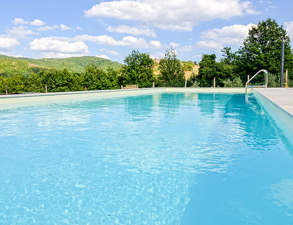 Vista ravvicinata della piscina esterna dell’Agriturismo Montelovesco. In fondo alla piscina si trovano delle scalette per entrare in acqua. Da bordo piscina è possibile ammirare il paesaggio collinare intorno all’area.