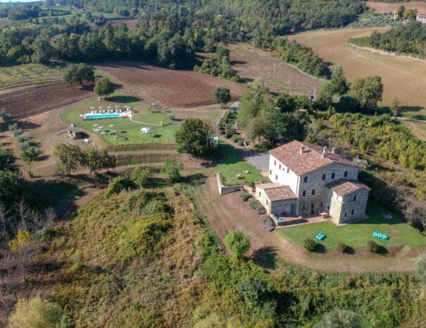 Vista dall’alto dell’area dell’Agriturismo Montelovesco, circondato da giardini, terreni coltivati, l’area piscina e solarium nel mezzo delle colline umbre.